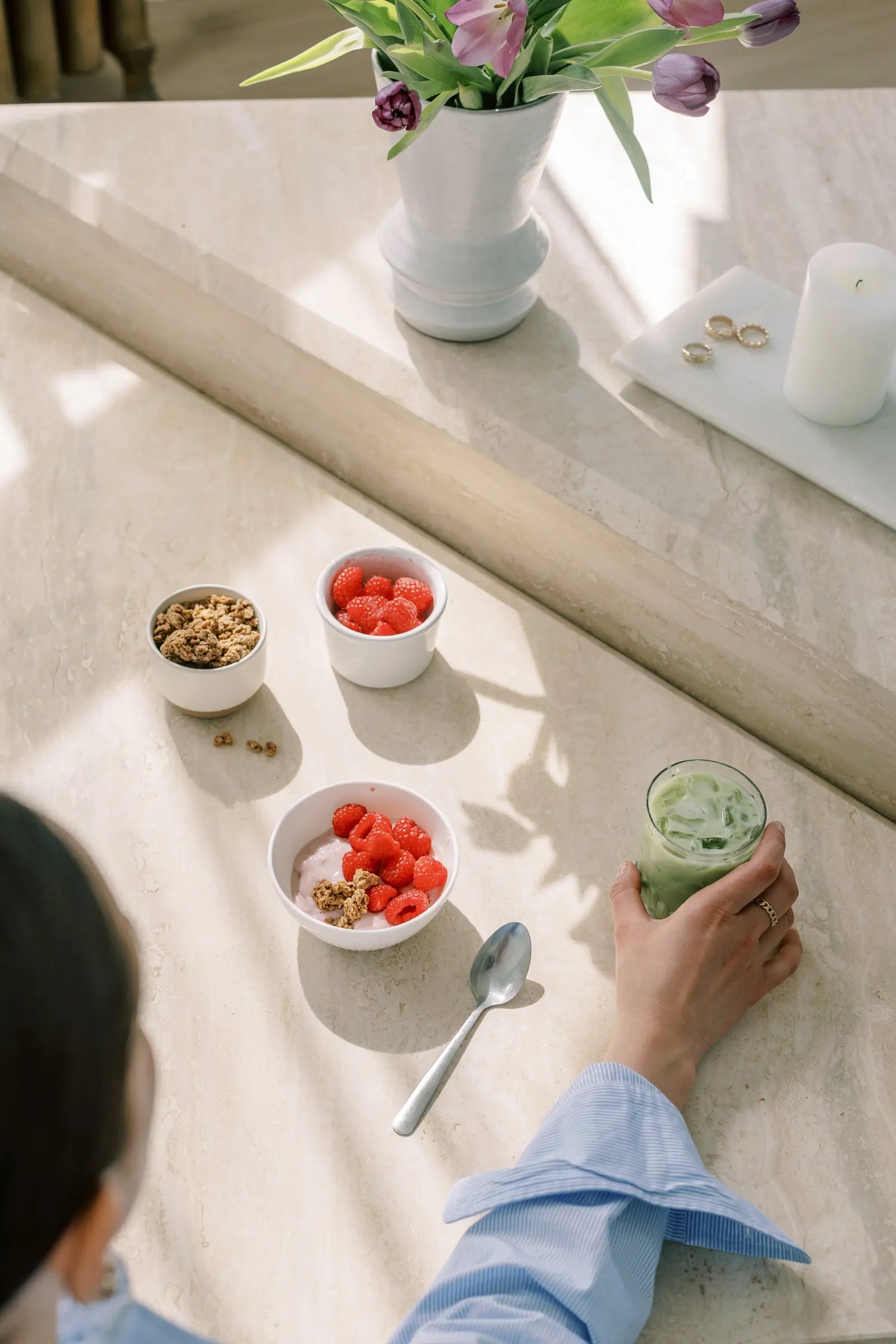 Mujer desayunando un bol de avena con frambuesas, granola y te matcha